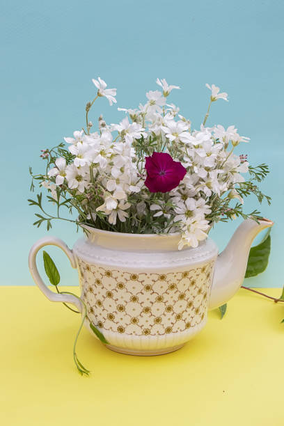 istock Beautiful summer bouquet in kettle on yellow-blue background 1242157063
