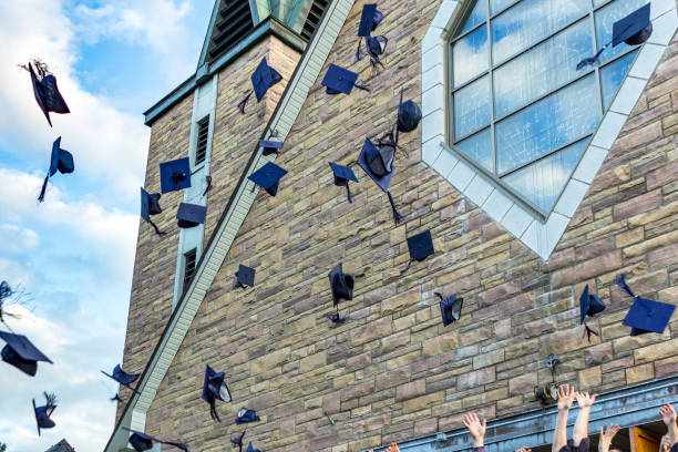 Rear view of three graduate students looking at sky