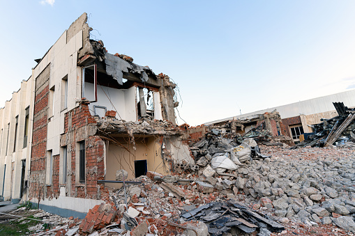 A pile of concrete debris on the background of a large destroyed building. Background. The concept of the consequences of human activities.