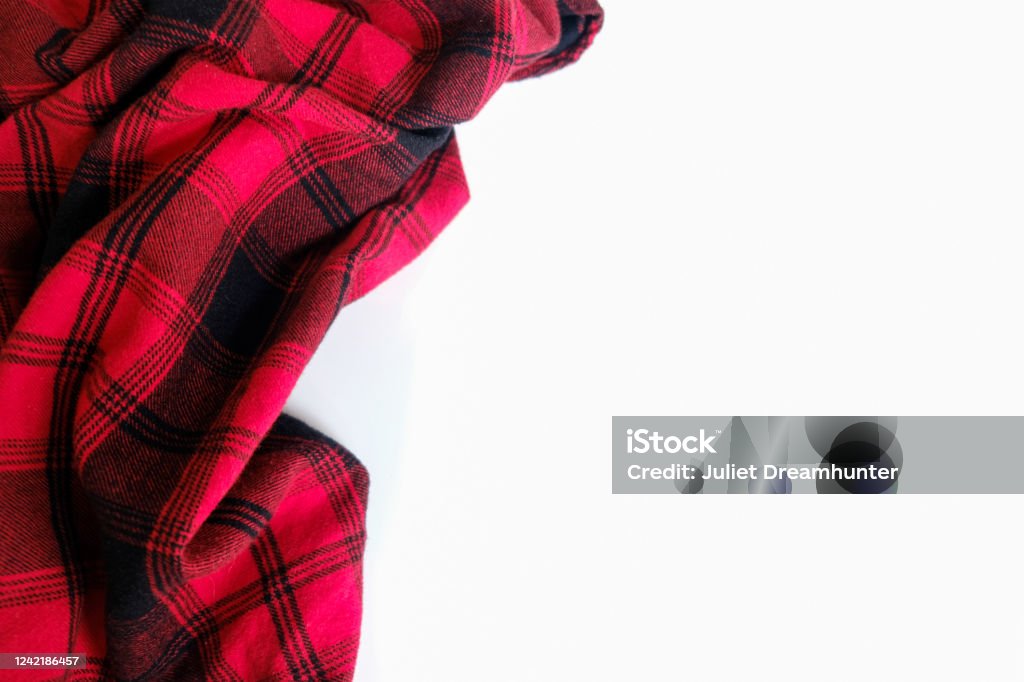 Bright red plaid wrinkled shirt on a white background Bright red plaid wrinkled shirt on a white background. Environment for working or studying from home. Empty surface surrounded by soft warm material. Cozy home office desk setting for isolation. Blanket Stock Photo