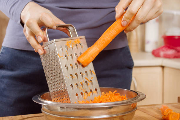 istock The woman's hands hold the carrot and rub it on the kitchen grater. 1242188045