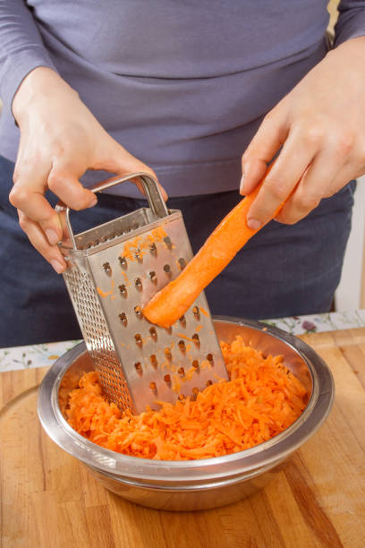 istock The woman's hands hold the carrot and rub it on the kitchen grater. 1242188054