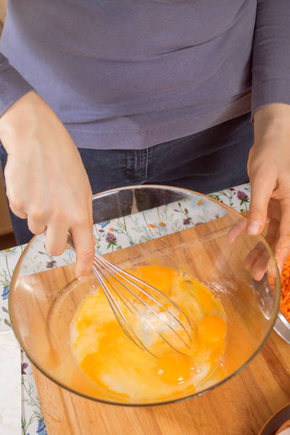 istock Woman whisks chicken eggs lying in a glass bowl with a kitchen whisk. 1242188564