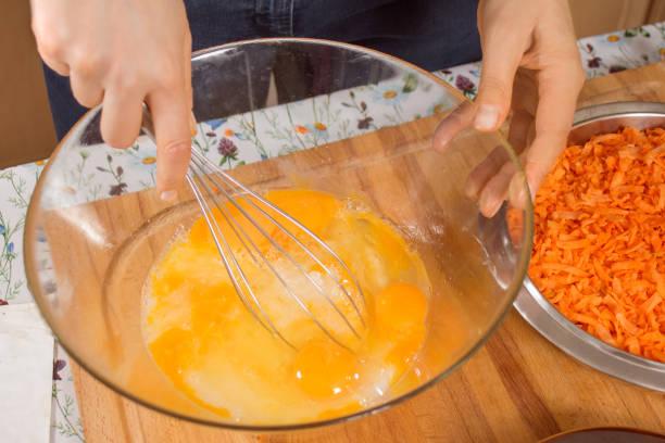 istock Woman whisks chicken eggs lying in a glass bowl with a kitchen whisk. 1242189092