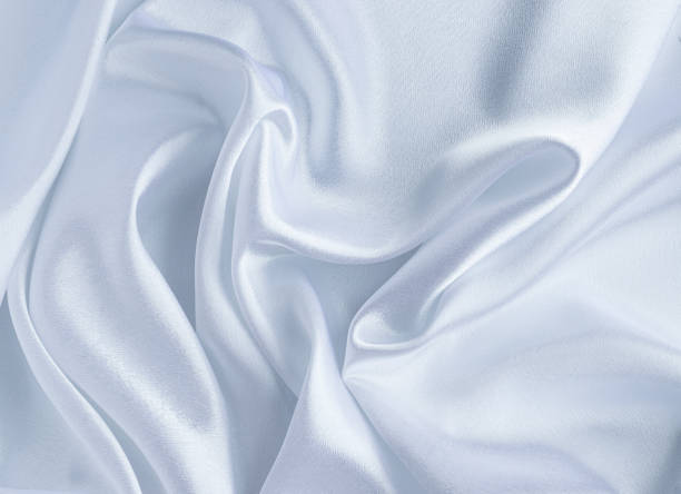 istock Satin white fabric close-up for backgrounds. The wavy silk texture 1242229345