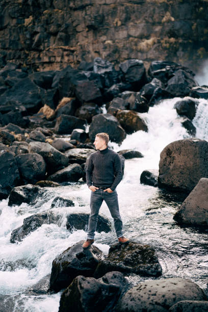 istock A guy in a black knitted sweater stands on rocks near Ehsaraurfoss Falls, Ehsarau River, National Park, Tingvedlir, Syudurland Region, Iceland. 1242242101