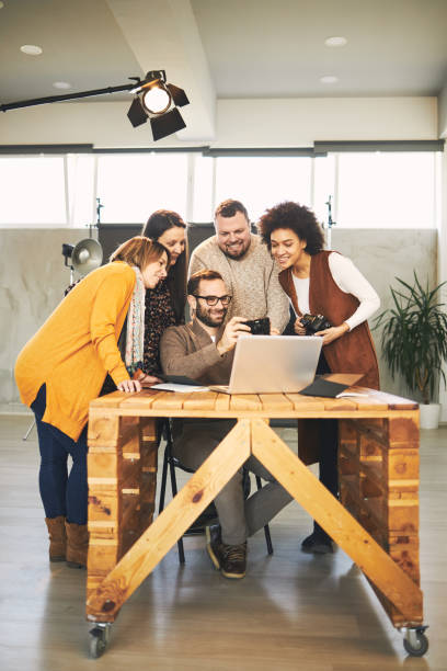 istock Young handsome bearded educator showing to his multicultural attendees how camera works. Photo studio interior. 1242242635