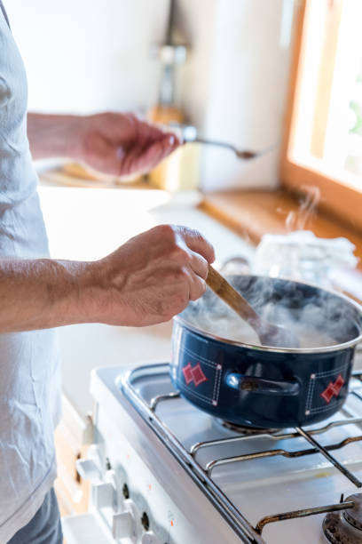 istock Content Man in Domestic Kitchen Melting Butter with Accuracy for Making Ghee 1242259707