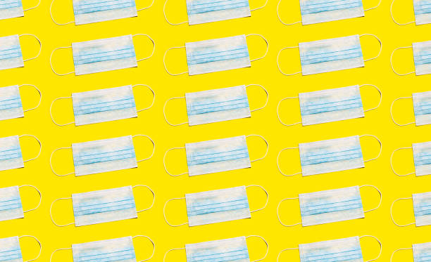 istock Pattern of medical flu mask isolated on yellow background. 1242276266