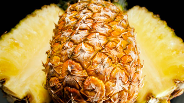 Closeup image of pineapple pieces over black backgound. Abstract background of exotic tropical fruits