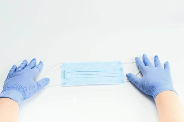 istock Hands  in gloves holding surgical mask. 1242295626