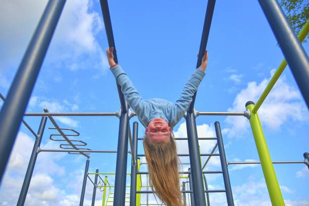 istock Little girl hanging upside down on parallel bars at playground. 1242307414
