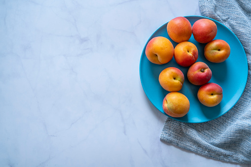 Apricots in a white marble background over a blue dish summer fruits