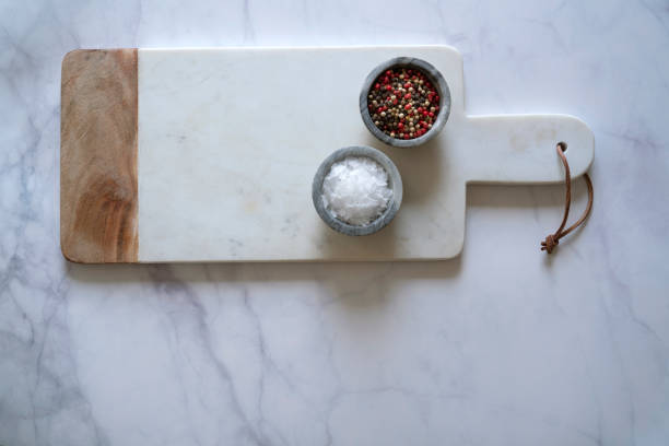istock White Marble cutting board on white marble counter with salt and pepper spices 1242347466