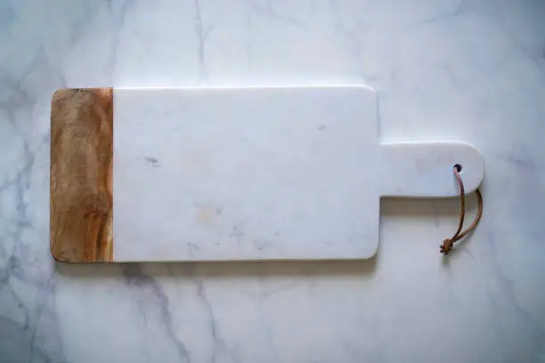 White Marble cutting board on white marble countertop monochromatic kitchen food background big copy space