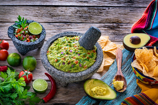 гуакамоле авокадо мексиканский рецепт в каменном molcajete с ингредиентами на дереве - salsa hot sauce mexico condiment стоковые фото и изображения