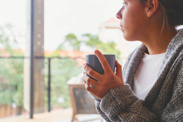 istock Woman looking through the window drinking tea or coffee. 1242398814