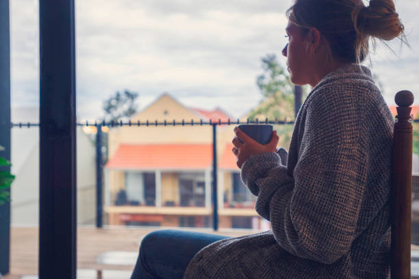 istock Woman looking through the window drinking tea or coffee. 1242398815