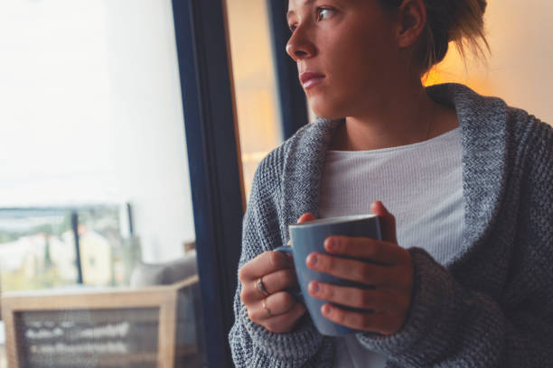 istock Woman looking through the window drinking tea or coffee. 1242398816