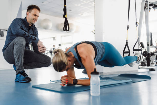 istock Woman doing plank on TRX while personal trainer is counting the time 1242454512