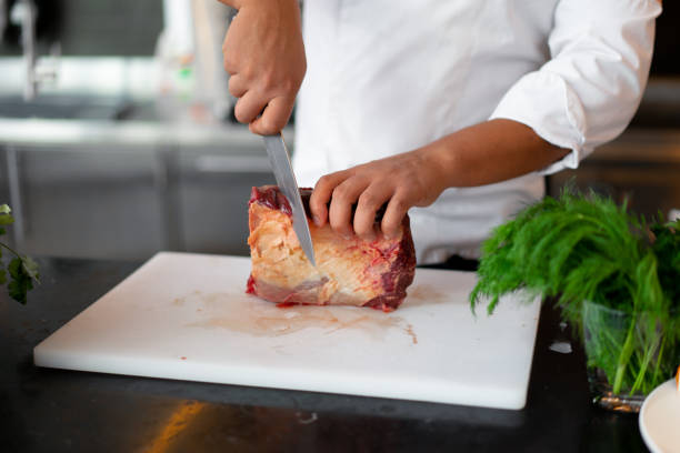 istock unrecognizable young African chef standing in professional kitchen in restaurant preparing a meal of meat and cheese vegetables. 1242460543