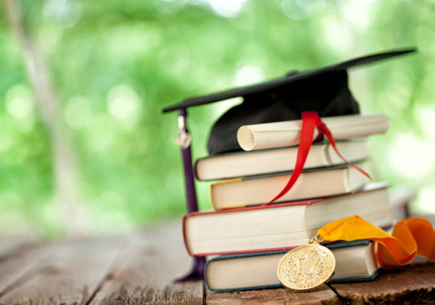 Graduation Concept Graduation cap on a stack of books with valedictorian medal of honor and diploma valedictorian stock pictures, royalty-free photos & images