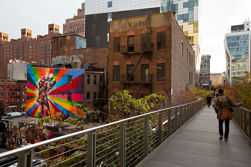New York, NY, United States - November 15th, 2012: High Line Park (with people walking on it), an old redeveloped railway line that became a suspended park in Manhattan. On the left a mural of brazilian artist Kobra.