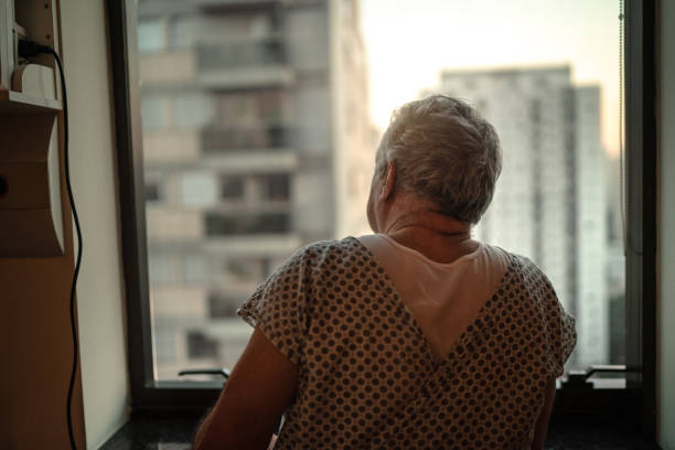 istock Senior patient looking through window at hospital 1242497268