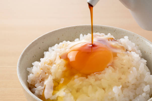 Soy sauce on rice with egg set against a wooden backdrop