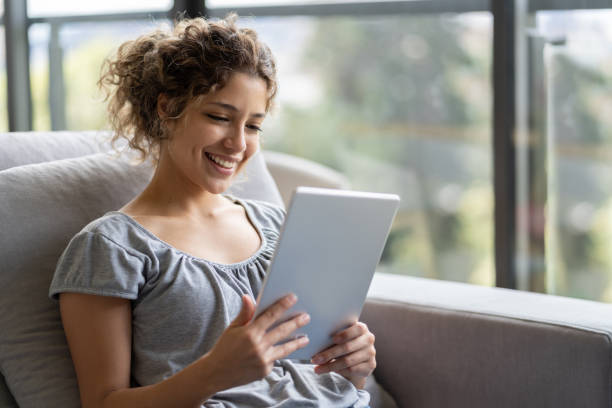 istock Happy woman at home during quarantine reading on her tablet 1242508925