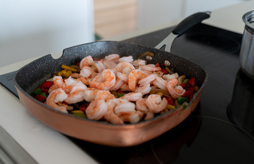 Close-up on a pan while cooking dinner at home and making a shrimp stir fry - healthy eating concepts