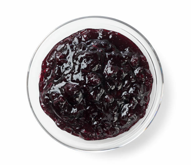 istock Blueberry jam in a glass bowl set against a white background 1242585403