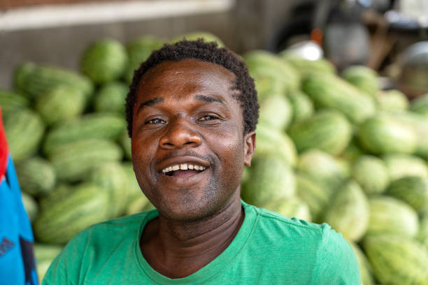 l'uomo africano vende angurie in un mercato locale di cibo di strada sull'isola di zanzibar, tanzania, africa orientale - africa agriculture zanzibar industry foto e immagini stock