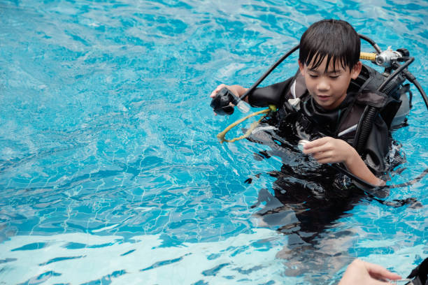 young little asian boy scuba diver checking pressure gauge and holding regulator, diving lessons for beginners - blue water swimming pool sports and fitness imagens e fotografias de stock