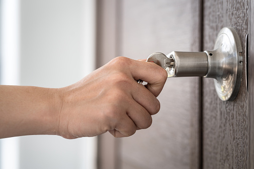 Action of people's hand is turning a house key to open the door. Close-up and selective focus on the key object (hand is slightly blurred).