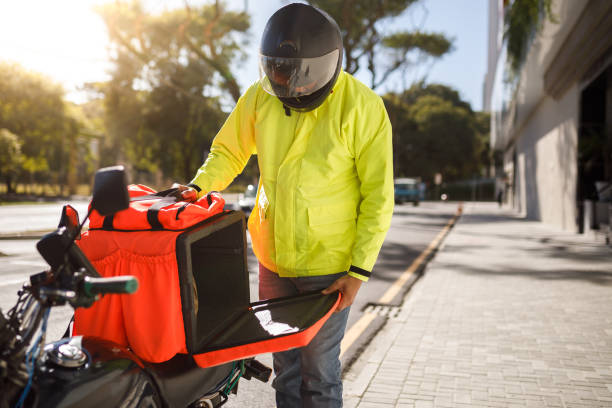 istock Delivery biker open his delivery backpack - motoboy 1242710115