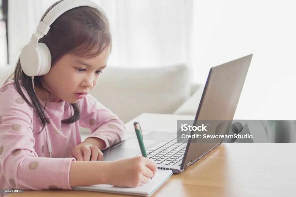 Girl making facetime video calling with laptop at home, using zoom online class meeting app, social distancing,homeschooling,learning remotely during covid-19 coronavirus, new normal concept Child Stock Photo