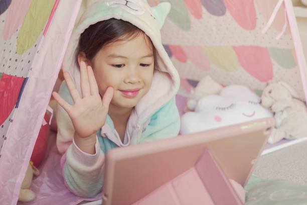 istock Mixed race Asian girl making facetime video calling with tablet at home, using zoom learning online app, social distancing, isolation, homeschooling education, learning remotely concept 1242722410