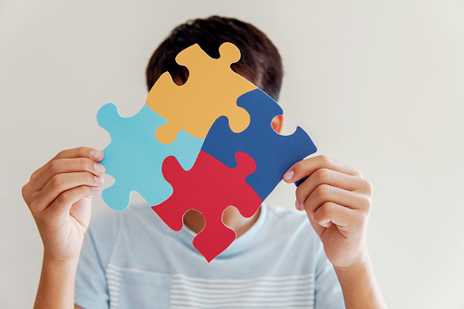 Kid boy hands holding puzzle jigsaw,  mental health concept, world autism awareness day