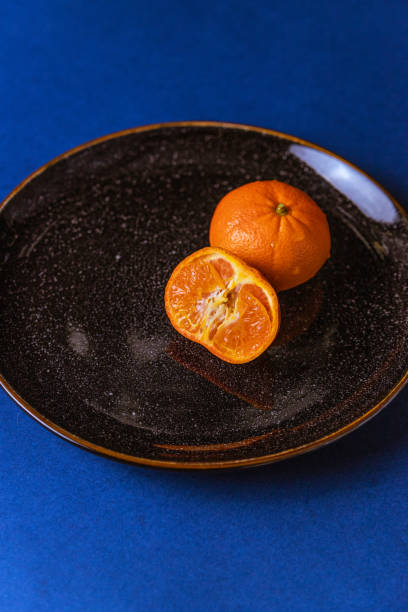 istock Tangerines on black plate on blue background. Citrus healthy fruit 1242782020