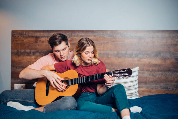 istock Nice couple resting at home and playing guitar 1242790152