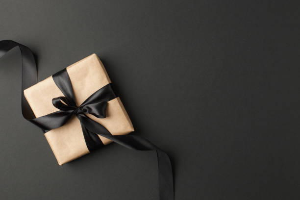 istock Gift or present craft box with black bow on black table top view. Flat lay composition for birthday, mother day, black friday sale, xmas, christmas, new year or wedding. 1242797677