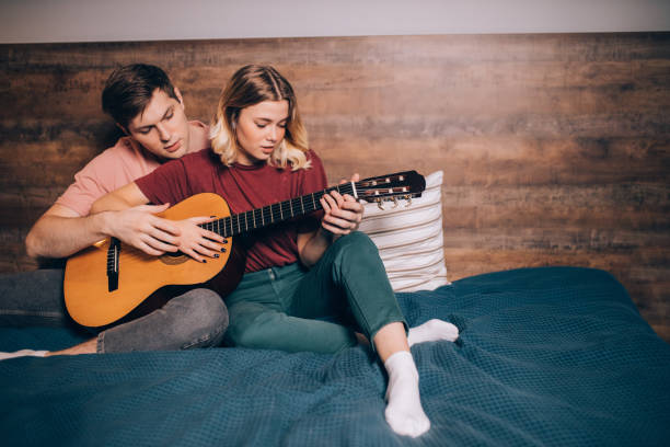 istock two friends playing the guitar at home 1242797688