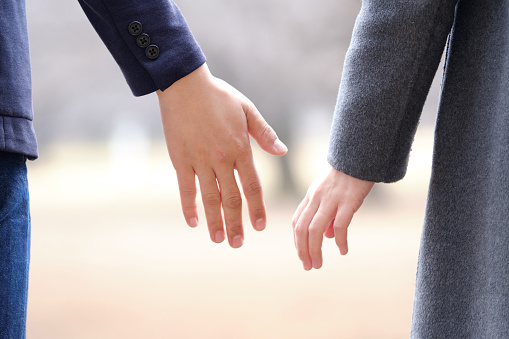 Un hombre y una mujer japoneses cogidos de la mano en un parque en invierno photo