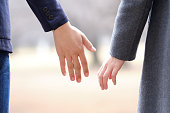 A Japanese man and woman holding hands in a park in winter