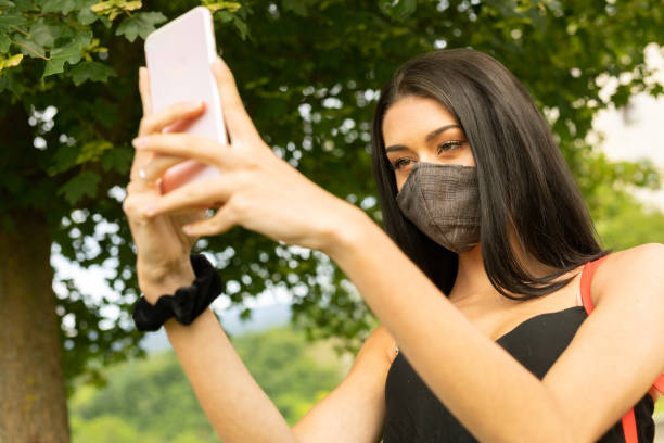 istock Young woman taking a selfie in a face mask 1242842375