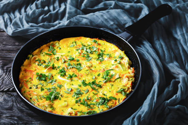 Healthy breakfast: vegetable and chicken eggs frittata of shredded  zucchini and carrot Fried omelette with zucchini, leek, and carrot served on a frying pan on a rustic wooden background sprinkled with fresh parsley on top, close-up frittata stock pictures, royalty-free photos & images