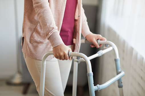 Close-up of senior woman using walker while moving along the room at home