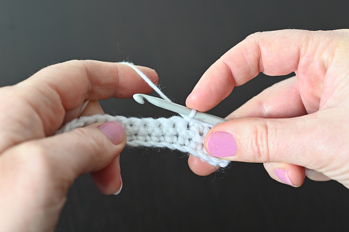 Detail of the hands of a woman crocheting with crochet needle