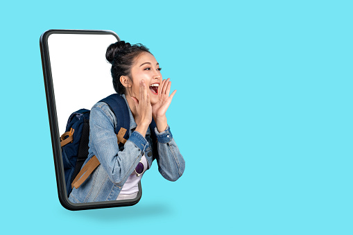 Smartphone pop up for advertising.Asian woman travel backpacker shouting open mouth through from screen mobile.Girl looking to aside copy space for present promotions.Digital marketing online cencept.